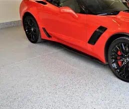 Red sports car parked on a full-flake mica-infused epoxy polyaspartic coated garage floor.